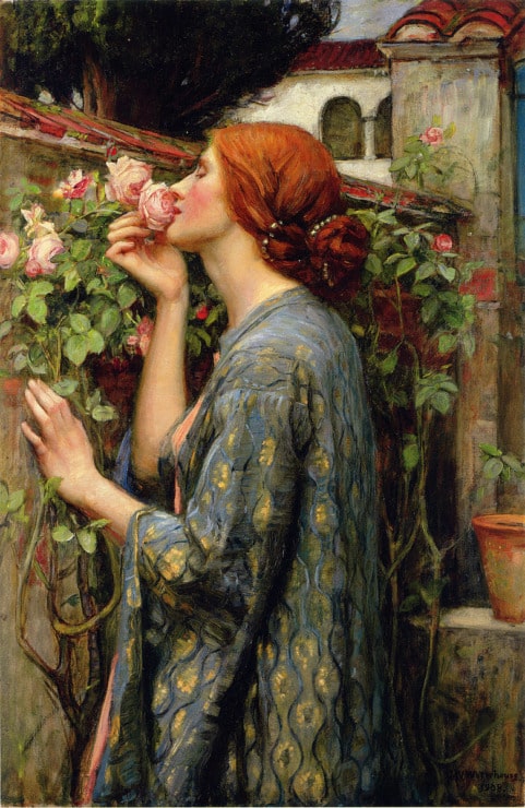 a woman holds a rose to her nose