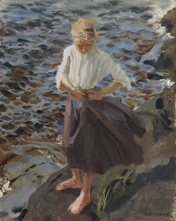 woman stands by the beach and her hair blows in the wind