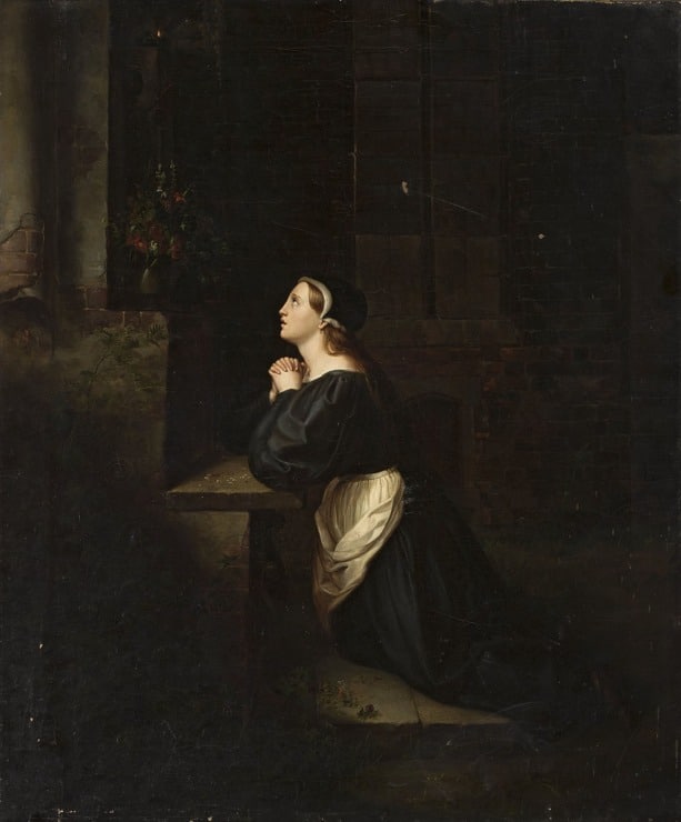 woman kneels with her hands clasped in prayer