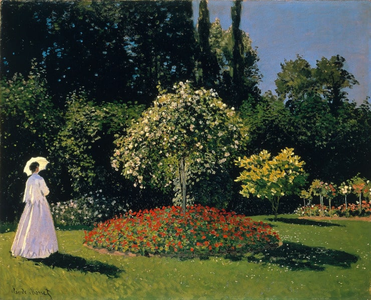 lady in white dress with a parasol stands in a garden